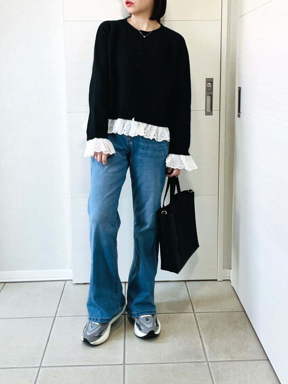 グレー系のスニーカー、ブルー系のデニムパンツ、ブラック系のカーディガン/ボレロを着用したレディースの春コーディネートの4枚目の写真