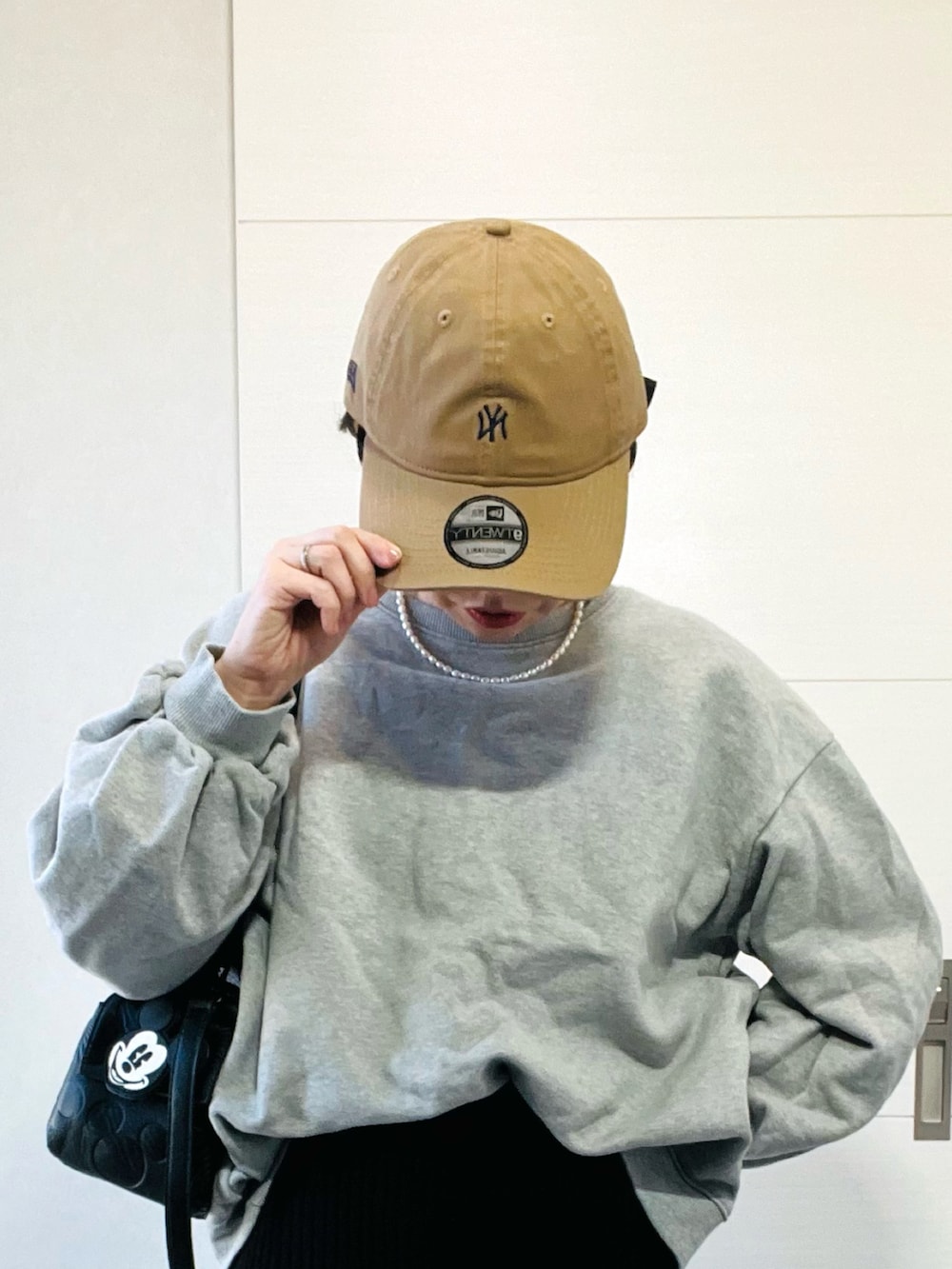 グレー系のスウェット、ブラック系のスカート、ブラック系のスニーカーを着用したレディースの秋コーディネートの2枚目の写真