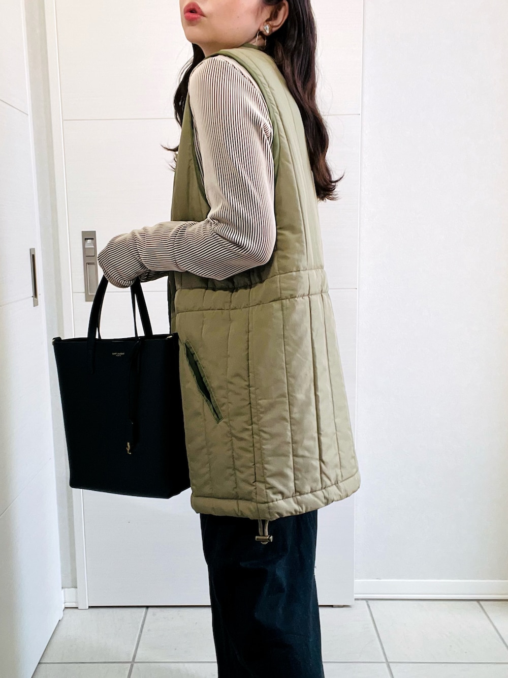 グリーン系のベスト、ベージュ系のTシャツ/カットソー、ブラック系のスカートを着用したレディースの秋コーディネートの4枚目の写真