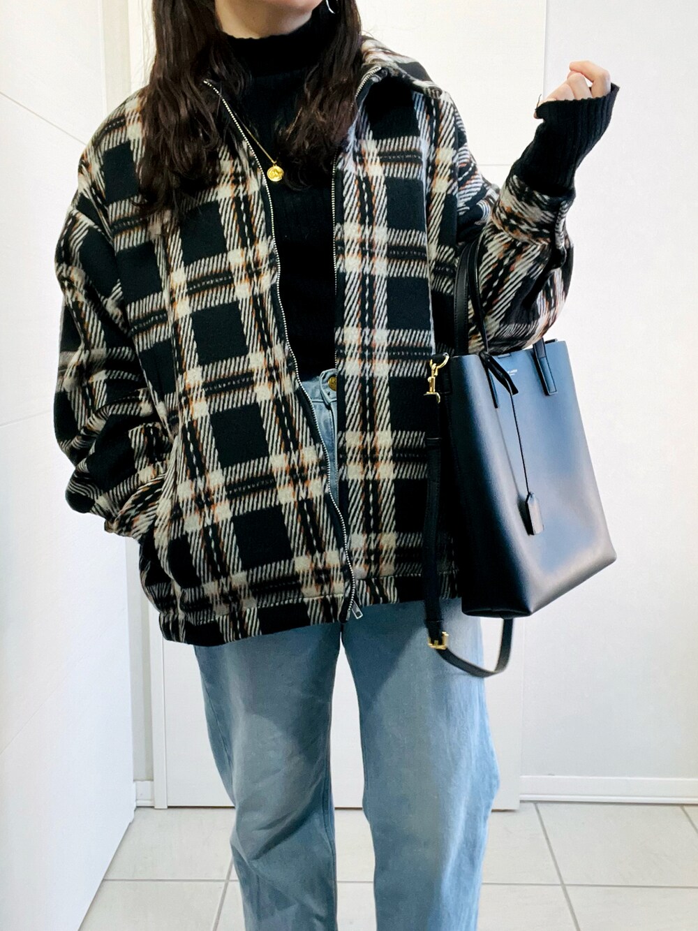 ブラック系のブルゾン、ブラック系のニット/セーター、ブルー系のデニムパンツを着用したレディースの冬コーディネートの2枚目の写真