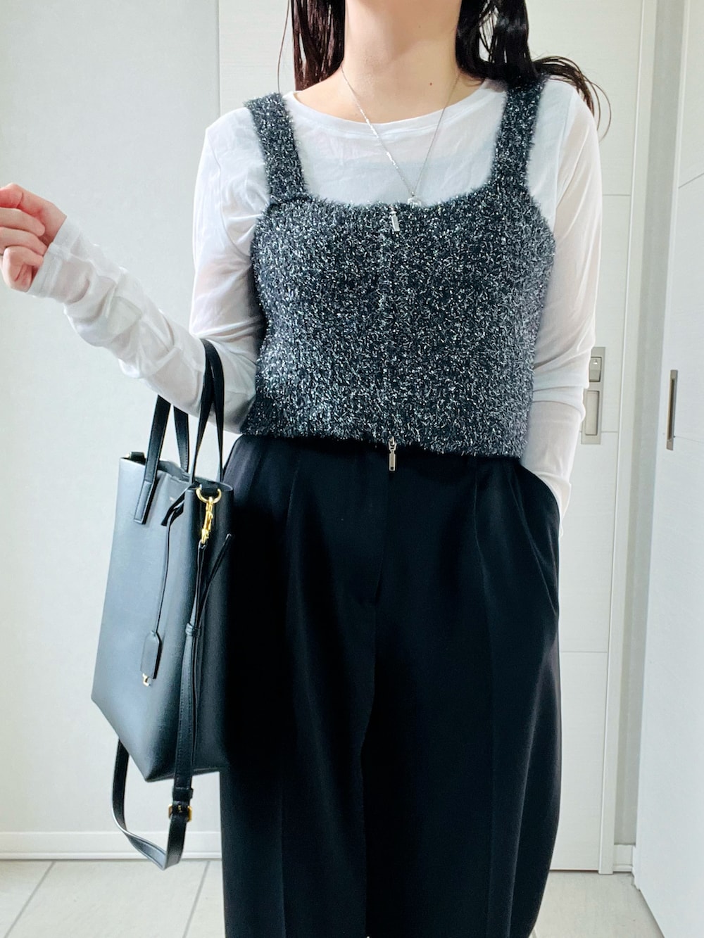 ブラック系のベスト、ホワイト系のTシャツ/カットソー、ブラック系のスラックスを着用したレディースの秋コーディネートの2枚目の写真