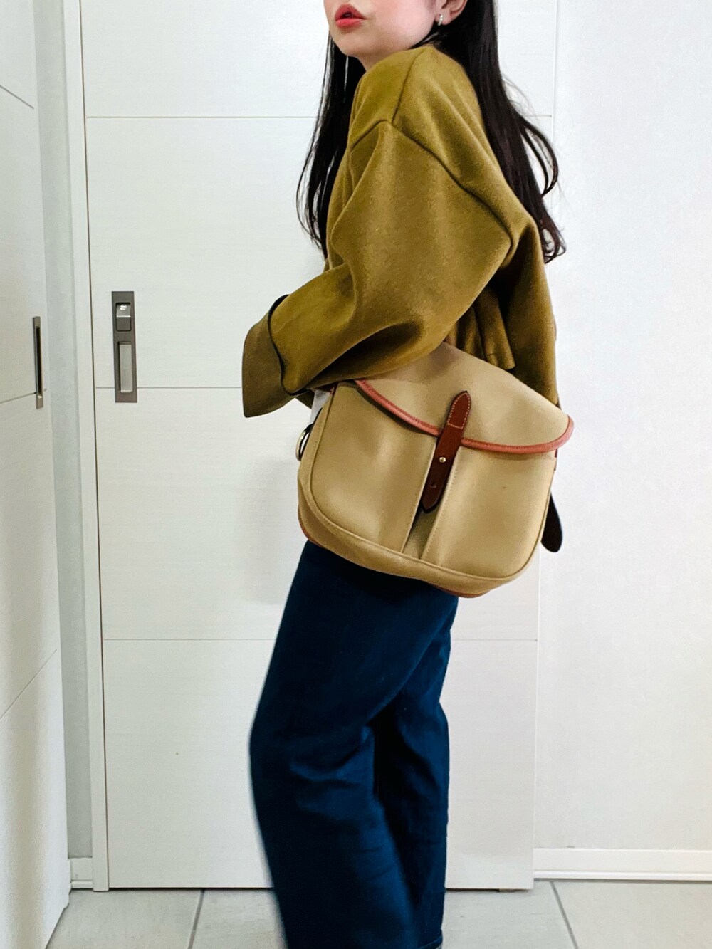グリーン系のワンピース、ブルー系のデニムパンツ、ブラック系のスニーカーを着用したレディースの冬コーディネートの4枚目の写真