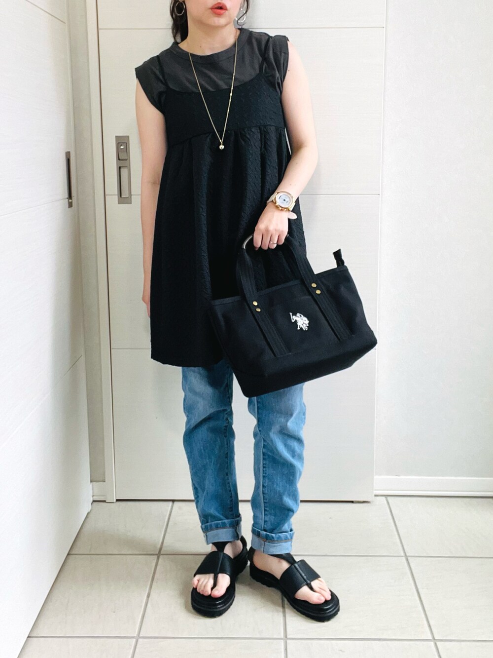 ブラック系のトートバッグ、ブラック系のワンピース、ブルー系のデニムパンツを着用したレディースの夏コーディネートの3枚目の写真