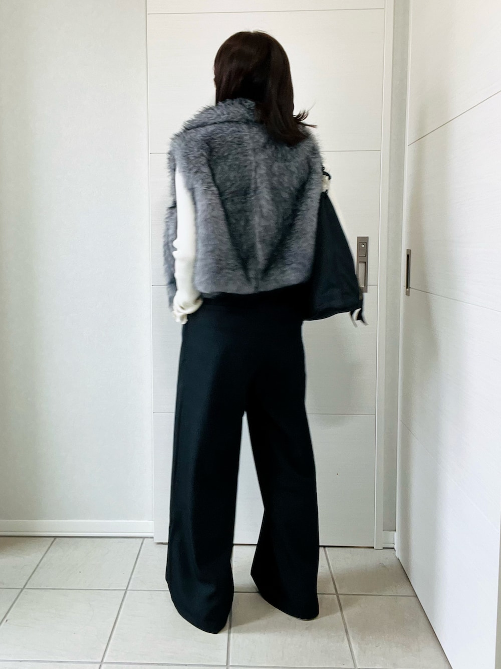 ホワイト系のニット/セーター、グレー系のベスト、ブラック系のスラックスを着用したレディースの秋コーディネートの5枚目の写真