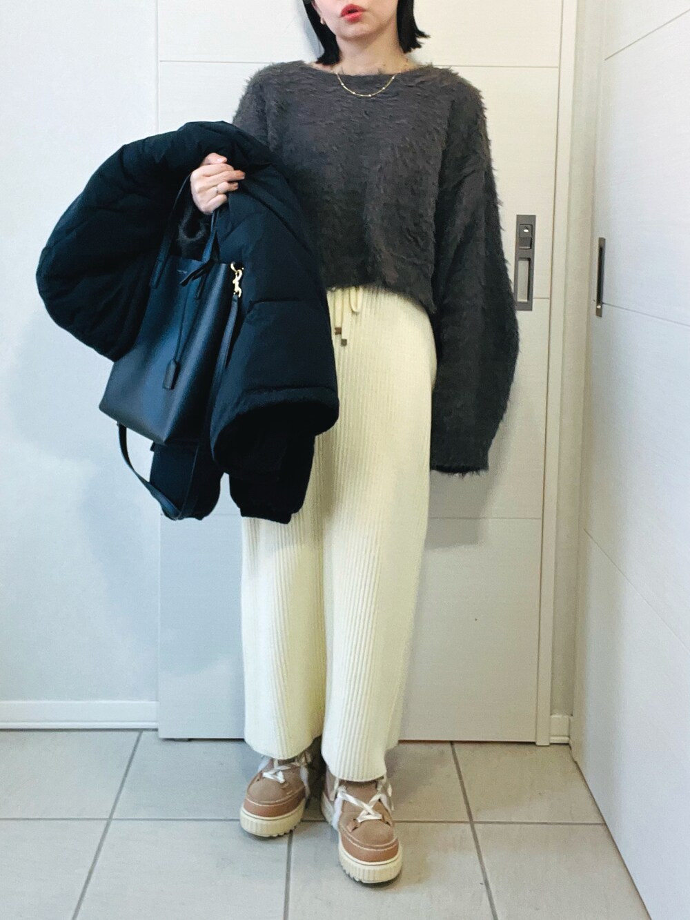 ブラック系のダウンジャケット/コート、グレー系のニット/セーター、ホワイト系のスカートを着用したレディースの冬コーディネートの4枚目の写真