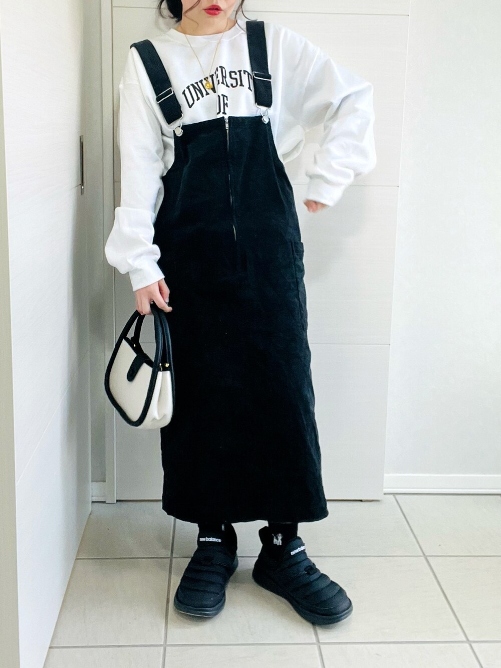 ホワイト系のダウンジャケット/コート、ホワイト系のスウェット、ブラック系のジャンパースカートを着用したレディースの冬コーディネートの3枚目の写真