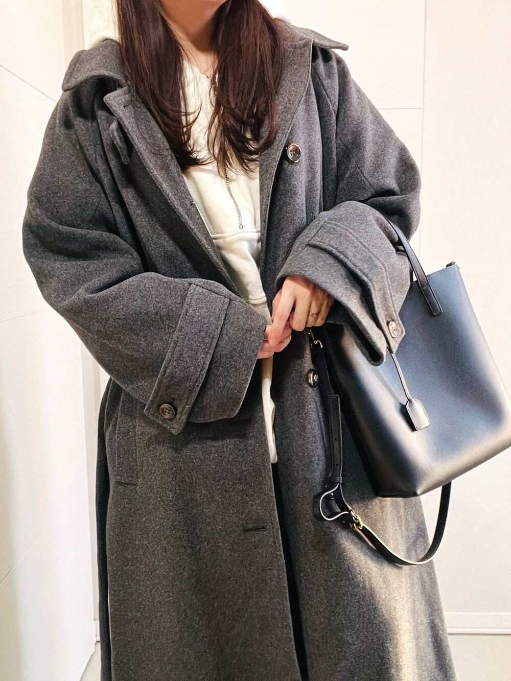 ホワイト系のパーカー、グレー系のステンカラーコート、ブルー系のデニムパンツを着用したレディースの冬コーディネートの5枚目の写真