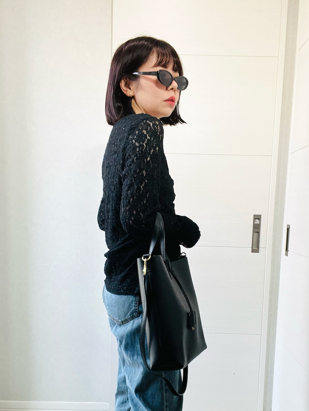 ブラック系のシャツ/ブラウス、ブラック系のブーツ、ブルー系のデニムパンツを着用したレディースの秋コーディネートの3枚目の写真