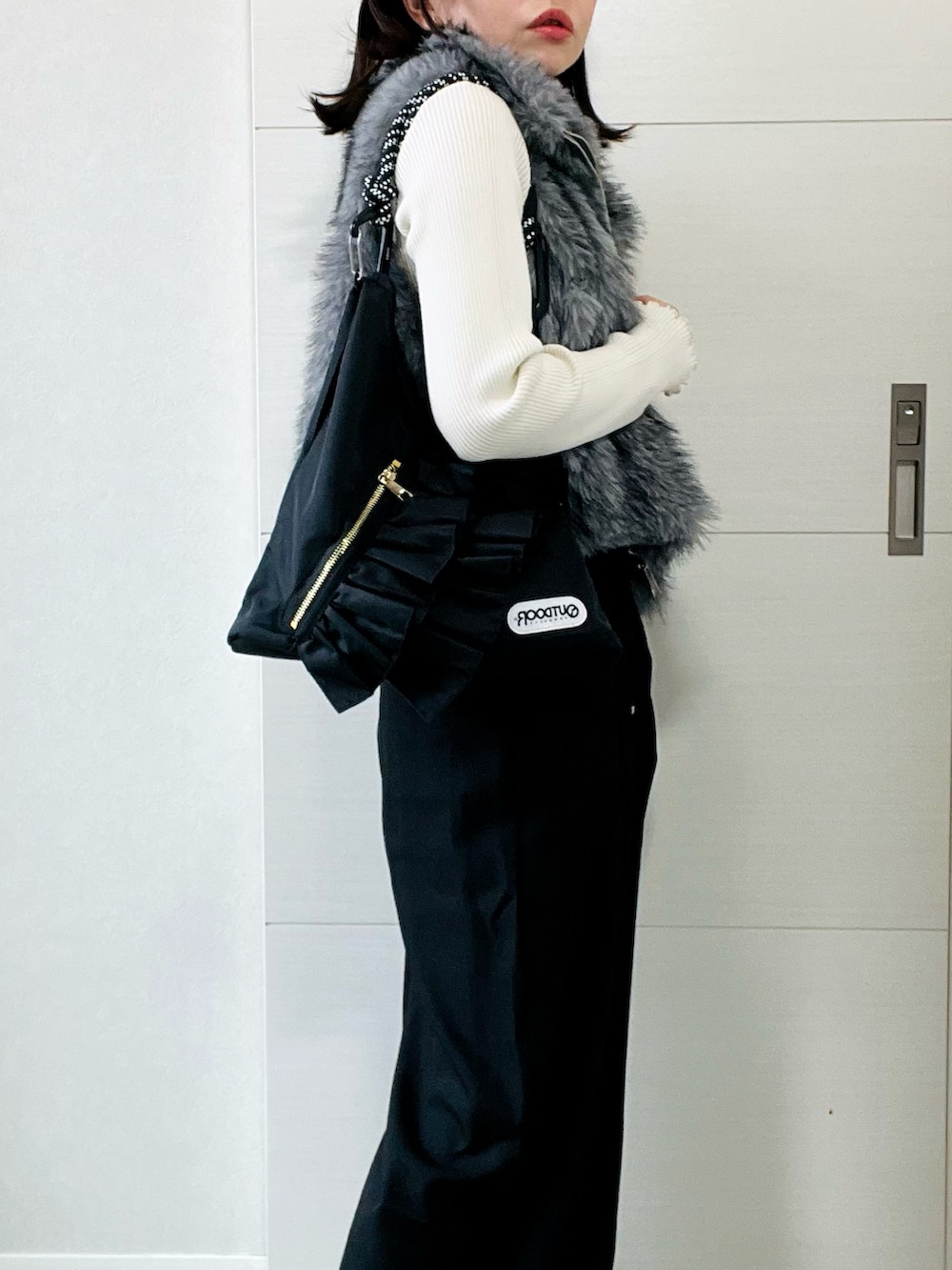 ホワイト系のニット/セーター、グレー系のベスト、ブラック系のスラックスを着用したレディースの秋コーディネートの3枚目の写真