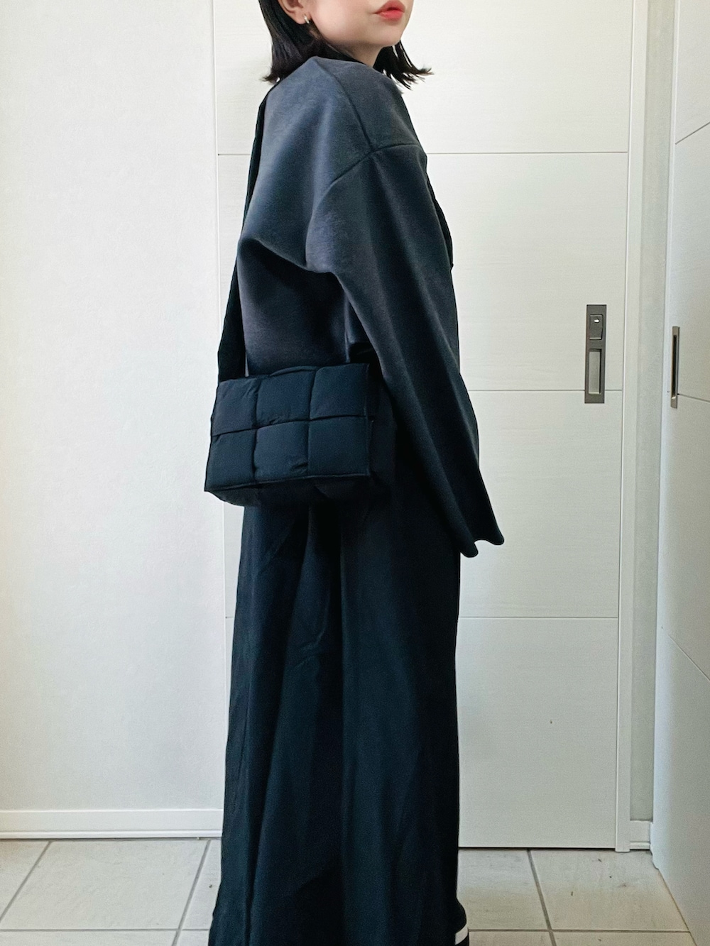 ブラック系のワンピース、ブラック系のショルダーバッグ、ブラック系のブーツを着用したレディースの秋コーディネートの3枚目の写真