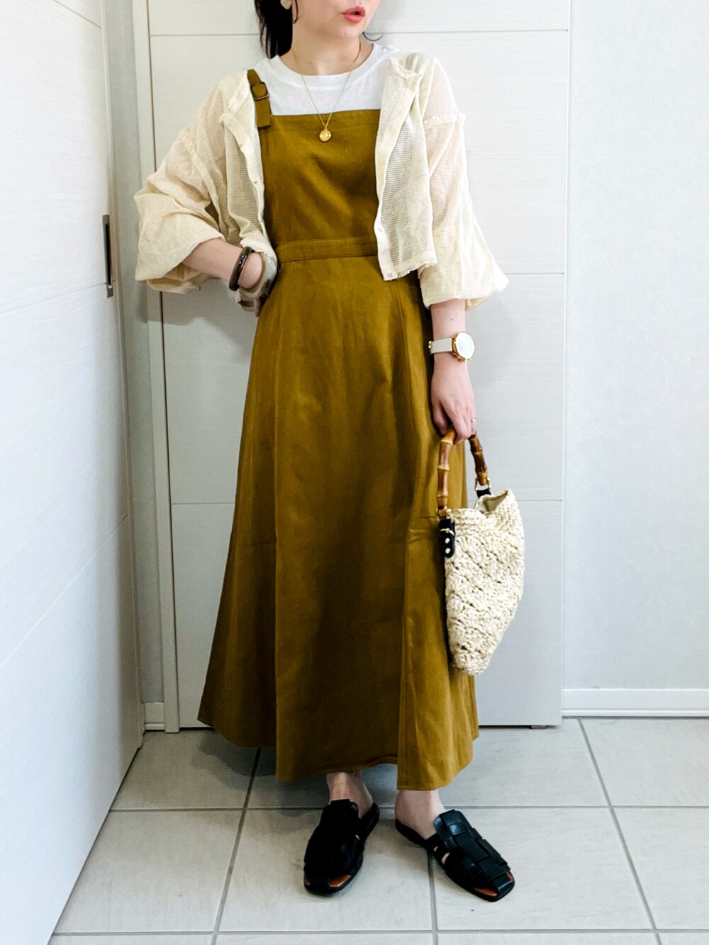 ホワイト系のカーディガン/ボレロ、イエロー系のワンピース、ブラック系のサンダルを着用したレディースの夏コーディネートの2枚目の写真