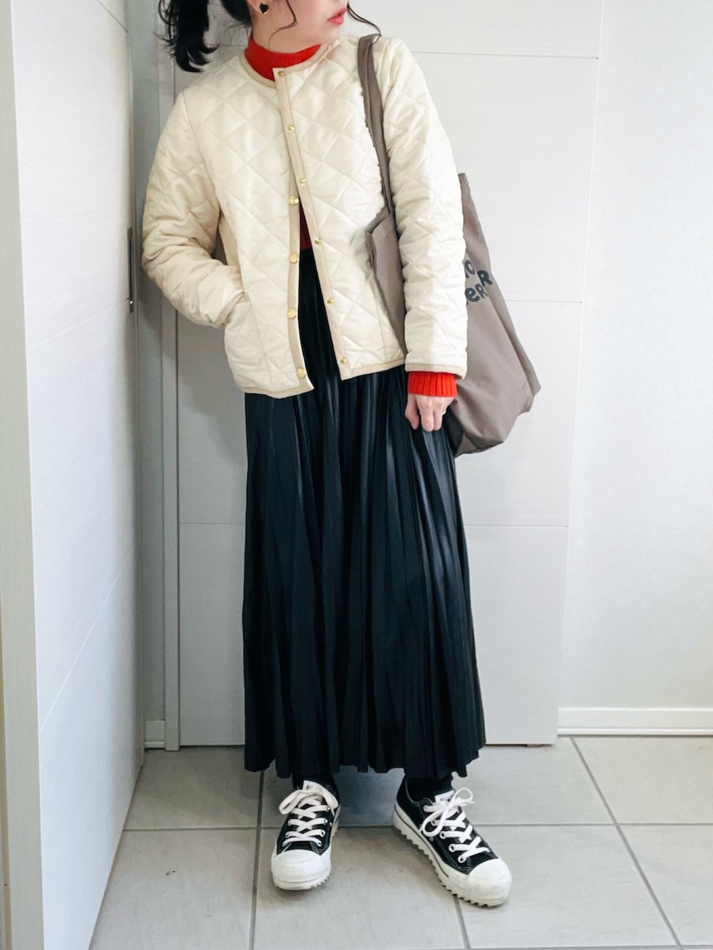 ホワイト系のノーカラージャケット、オレンジ系のニット/セーター、ブラック系のスカートを着用したレディースの秋コーディネートの3枚目の写真