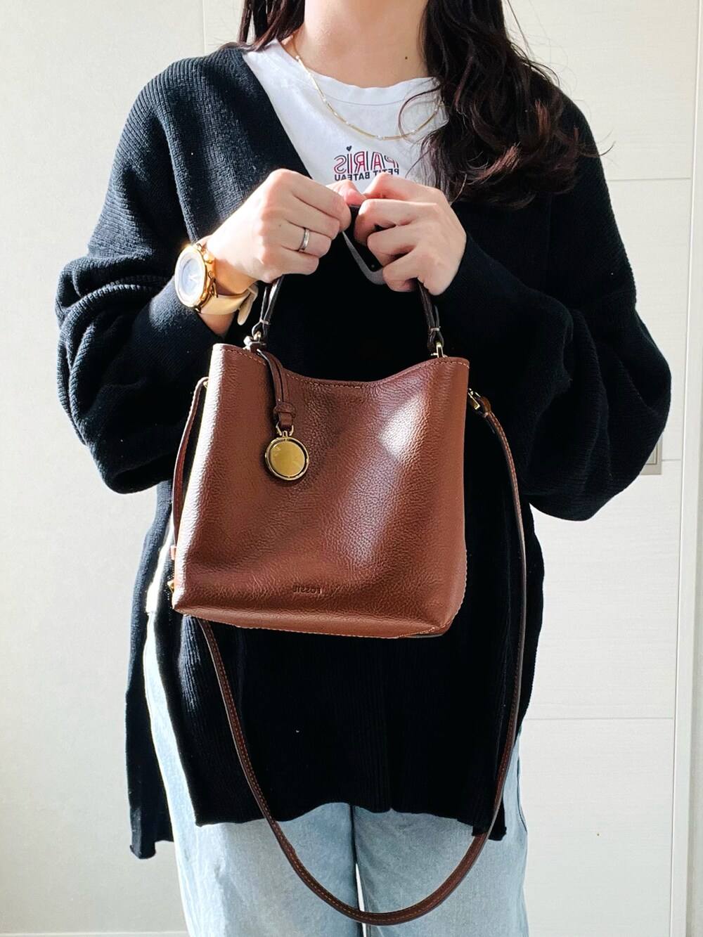 ブラウン系のショルダーバッグ、ホワイト系のTシャツ/カットソー、ブラック系のニット/セーターを着用したレディースの秋コーディネートの3枚目の写真