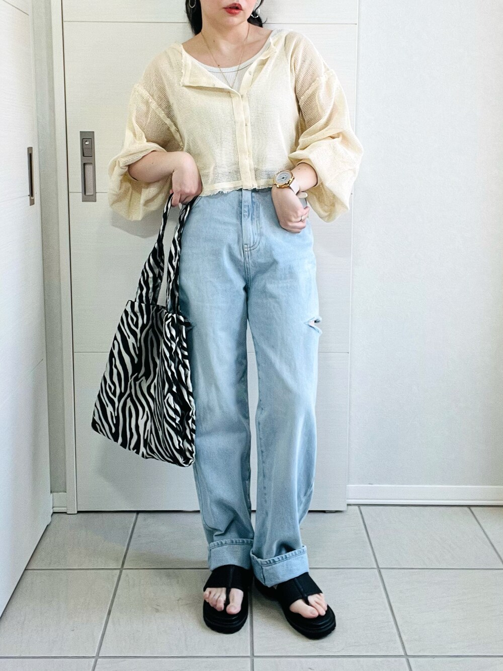 ホワイト系のカーディガン/ボレロ、ブルー系のデニムパンツ、ブラック系のサンダルを着用したレディースの春コーディネートの3枚目の写真