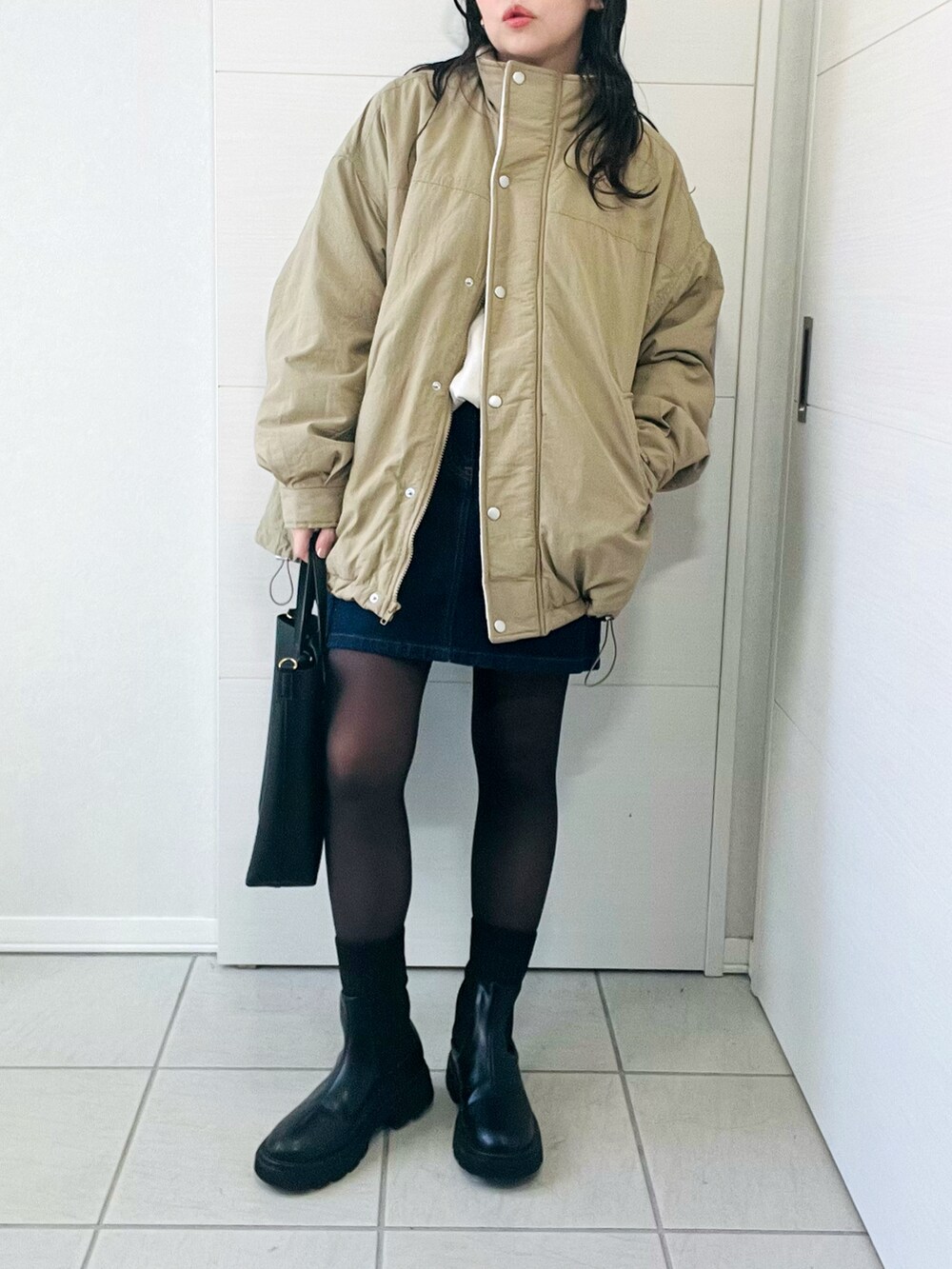 ベージュ系のブルゾン、ホワイト系のニット/セーター、ブルー系のデニムスカートを着用したレディースの秋コーディネートの4枚目の写真