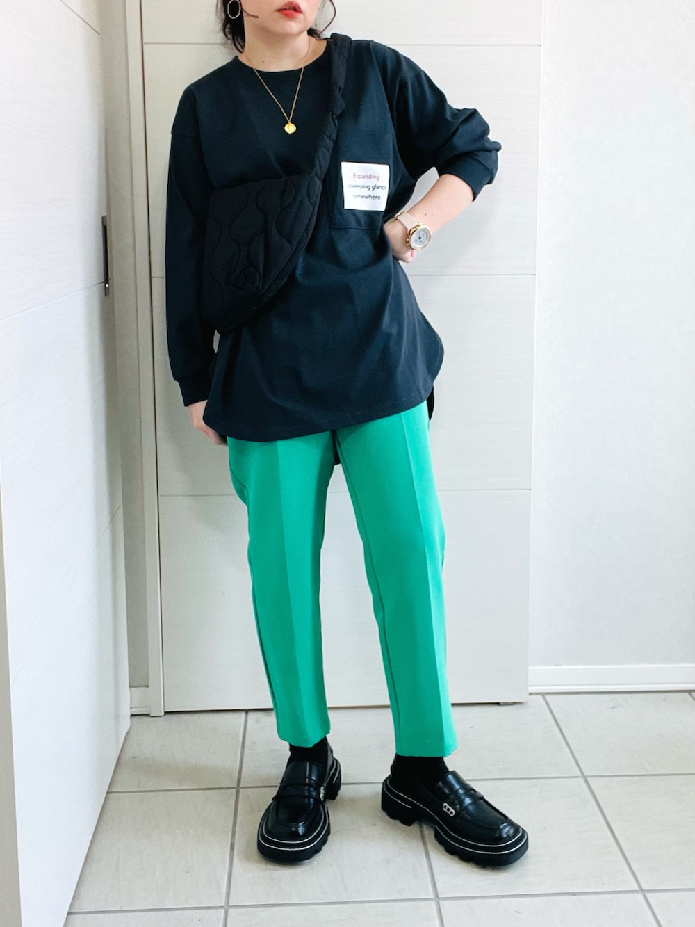 ブラック系のTシャツ/カットソー、グリーン系のスラックス、ブラック系のローファーを着用したレディースの春コーディネートの3枚目の写真