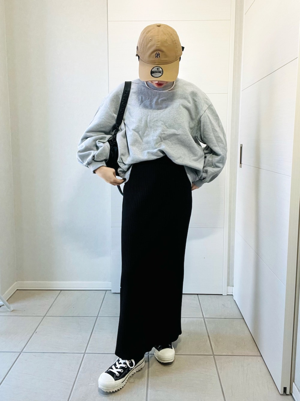 グレー系のスウェット、ブラック系のスカート、ブラック系のスニーカーを着用したレディースの秋コーディネートの4枚目の写真