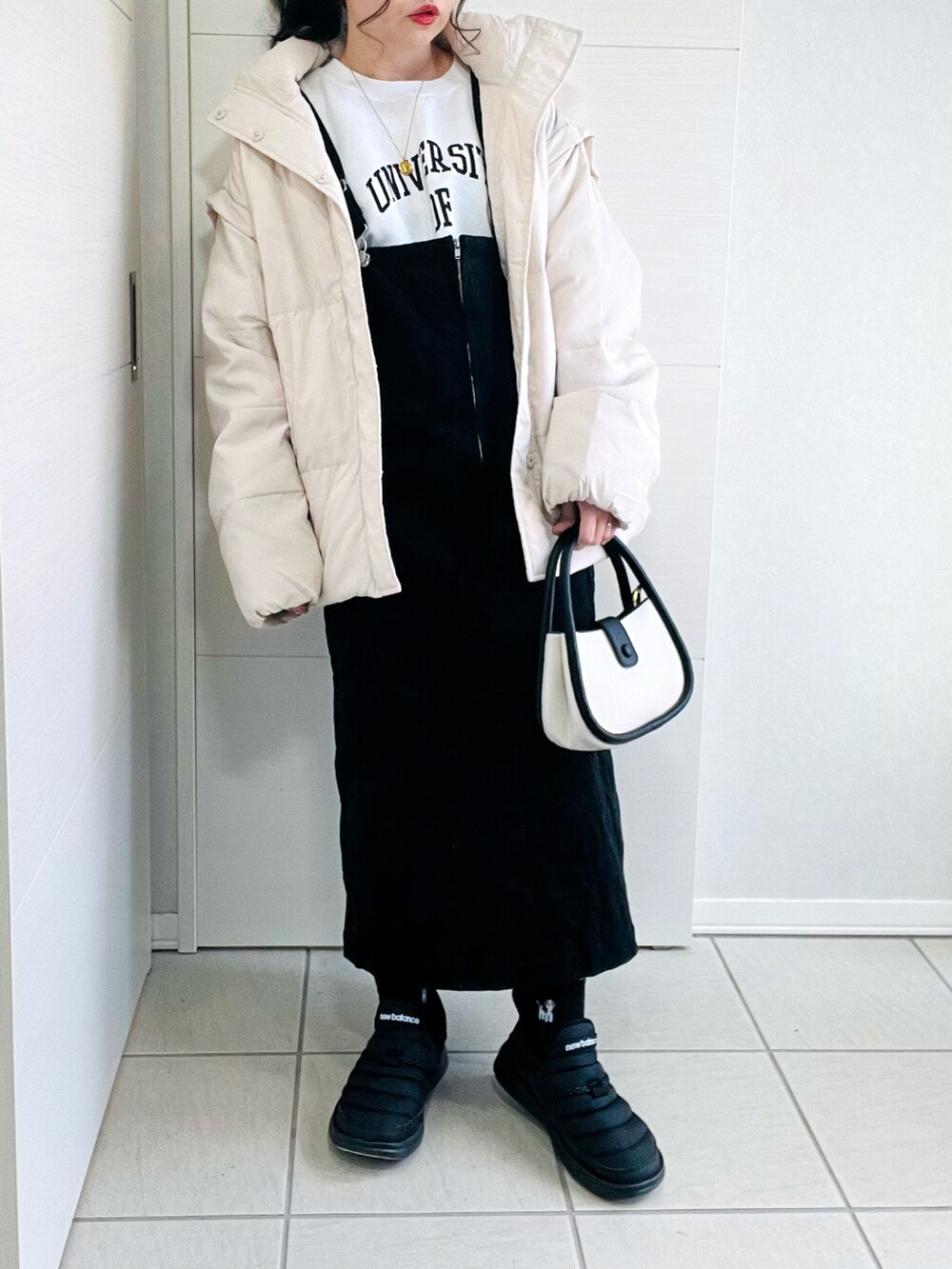 ホワイト系のダウンジャケット/コート、ホワイト系のスウェット、ブラック系のジャンパースカートを着用したレディースの冬コーディネートの4枚目の写真