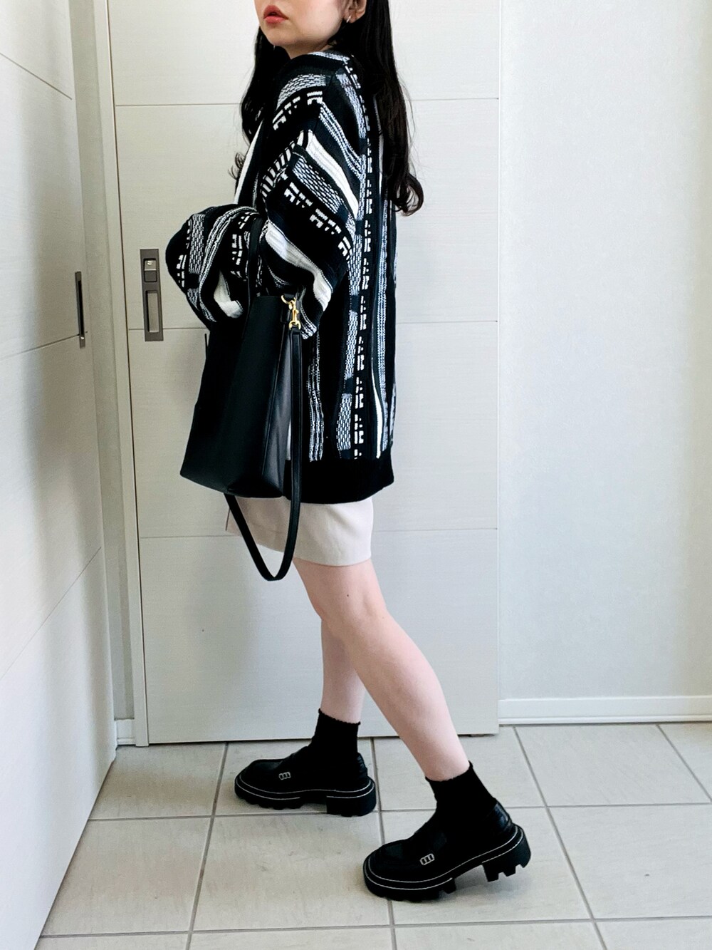 ブラック系のカーディガン/ボレロ、ホワイト系のスラックス、ブラック系のローファーを着用したレディースの春コーディネートの5枚目の写真