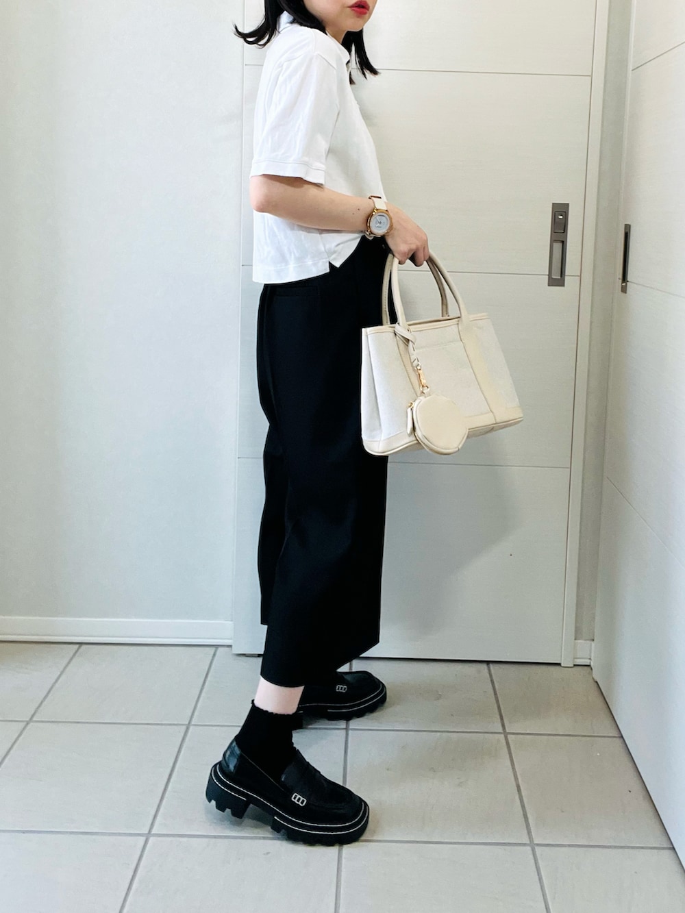 ホワイト系のポロシャツ、ブラック系のその他パンツ、ホワイト系のトートバッグを着用したレディースの夏コーディネートの5枚目の写真