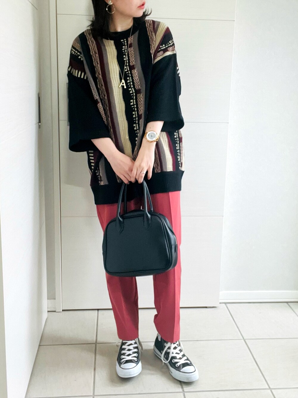 レッド系のニット/セーター、レッド系のスラックス、ブラック系のスニーカーを着用したレディースの夏コーディネートの2枚目の写真