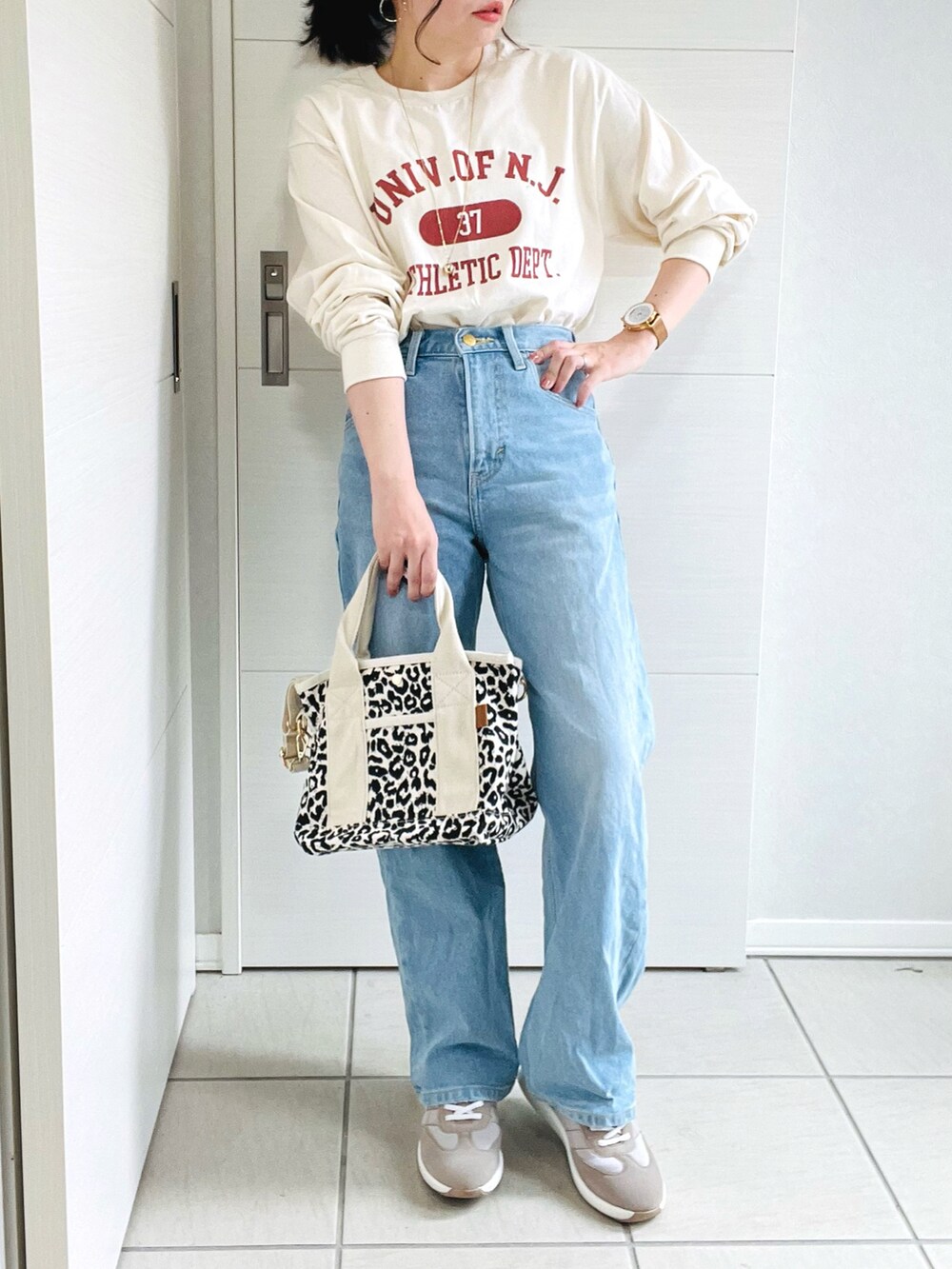 ベージュ系のTシャツ/カットソー、ブルー系のデニムパンツ、ベージュ系のスニーカーを着用したレディースの夏コーディネートの2枚目の写真