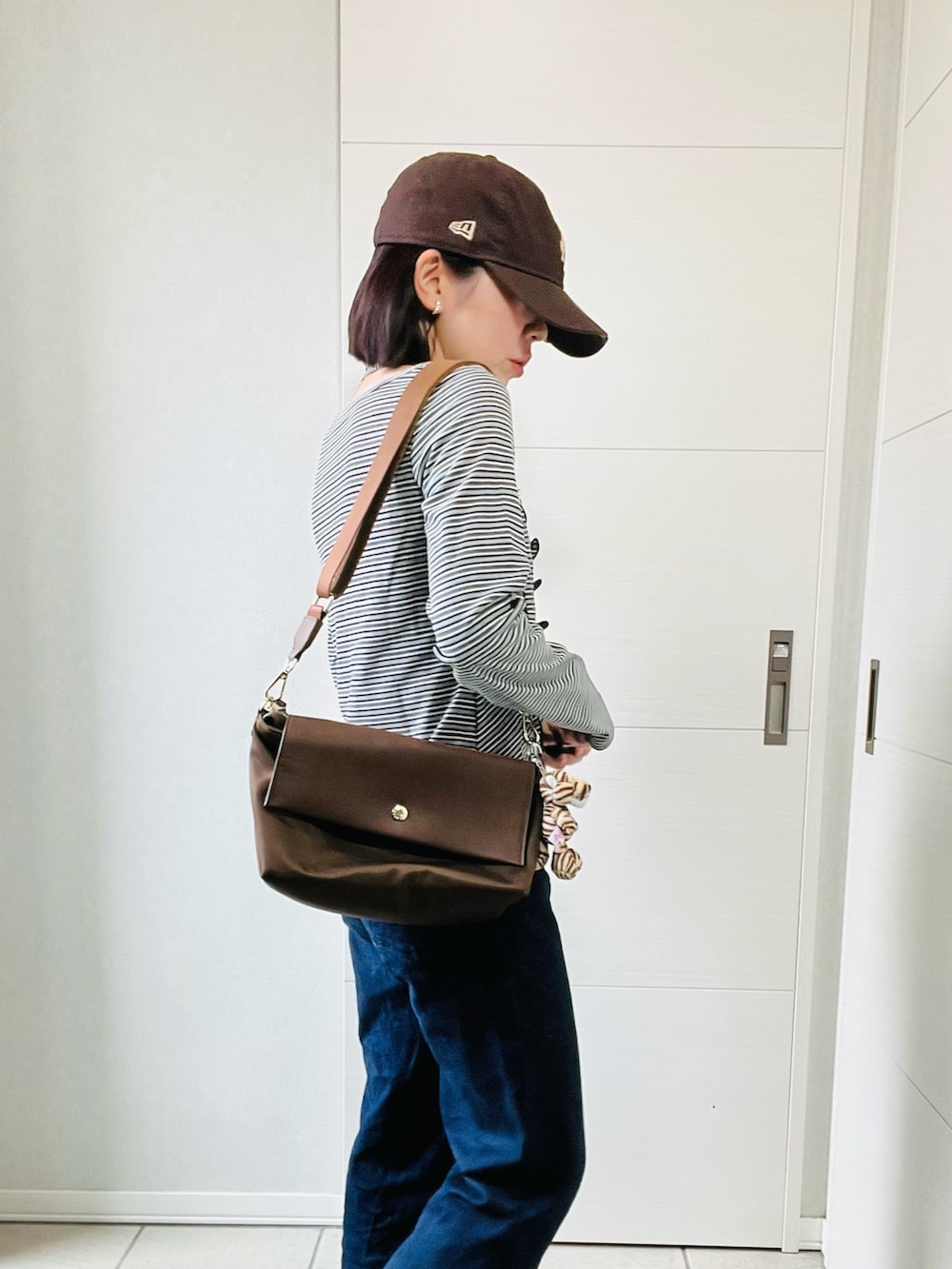 ブラック系のTシャツ/カットソー、ブラウン系のスニーカー、ブルー系のデニムパンツを着用したレディースの秋コーディネートの3枚目の写真
