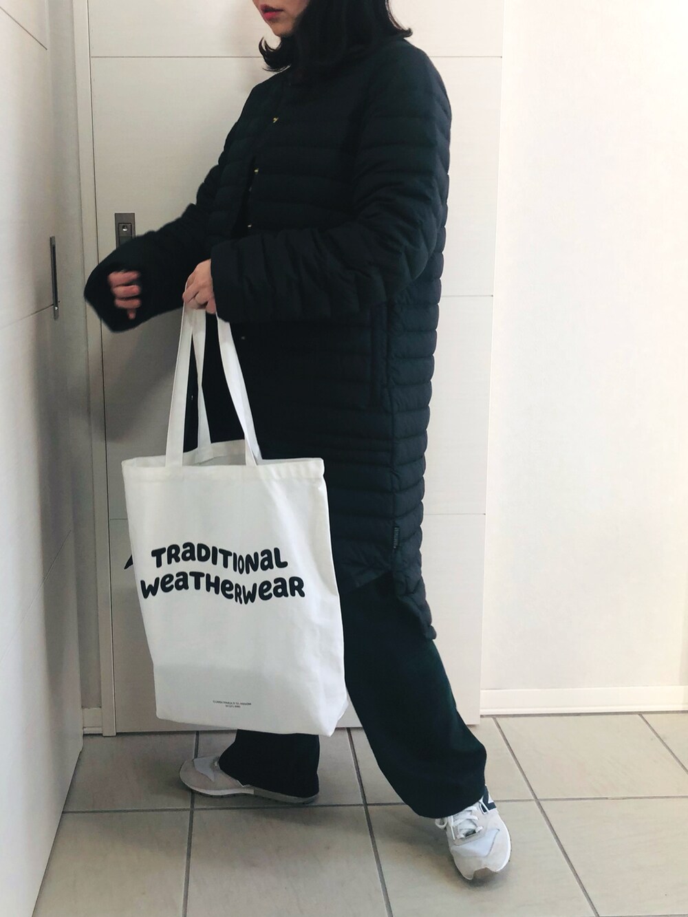 ブラック系のダウンジャケット/コート、ブラック系のニット/セーター、グリーン系のスラックスを着用したレディースの冬コーディネートの3枚目の写真