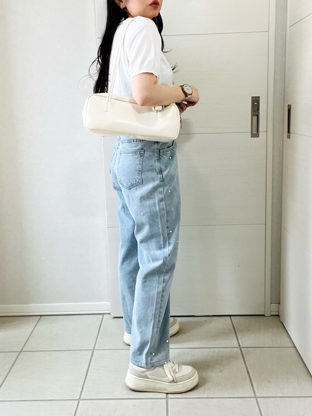 ホワイト系のニット/セーター、ブルー系のデニムパンツ、ホワイト系のスニーカーを着用したレディースの夏コーディネートの5枚目の写真