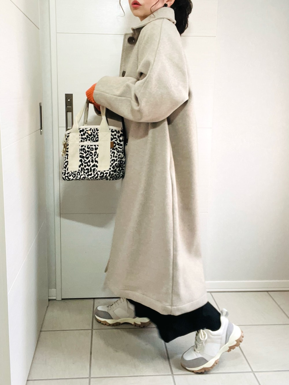 ベージュ系のステンカラーコート、ベージュ系のTシャツ/カットソー、ブラック系のワンピースを着用したレディースの秋コーディネートの5枚目の写真