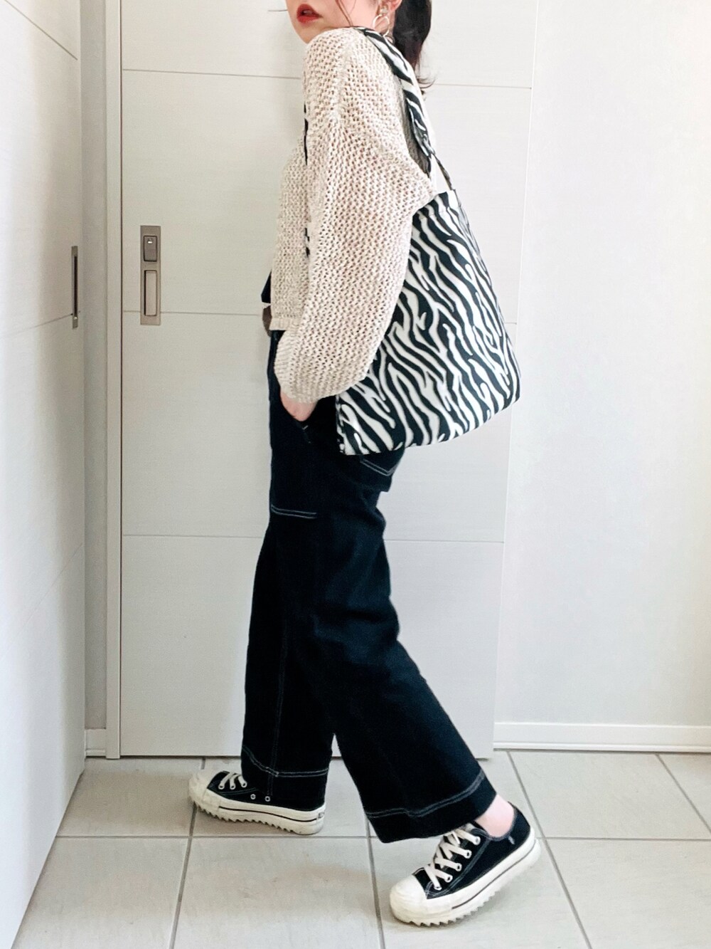 ベージュ系のニット/セーター、ブラック系のデニムパンツ、ブラック系のスニーカーを着用したレディースの春コーディネートの4枚目の写真