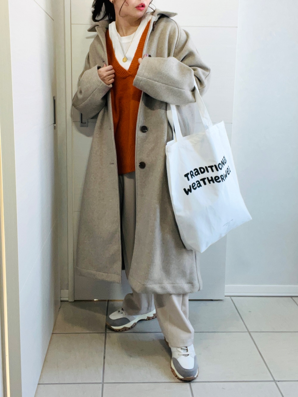 オレンジ系のニット/セーター、ホワイト系のスラックス、ベージュ系のスニーカーを着用したレディースの冬コーディネートの4枚目の写真