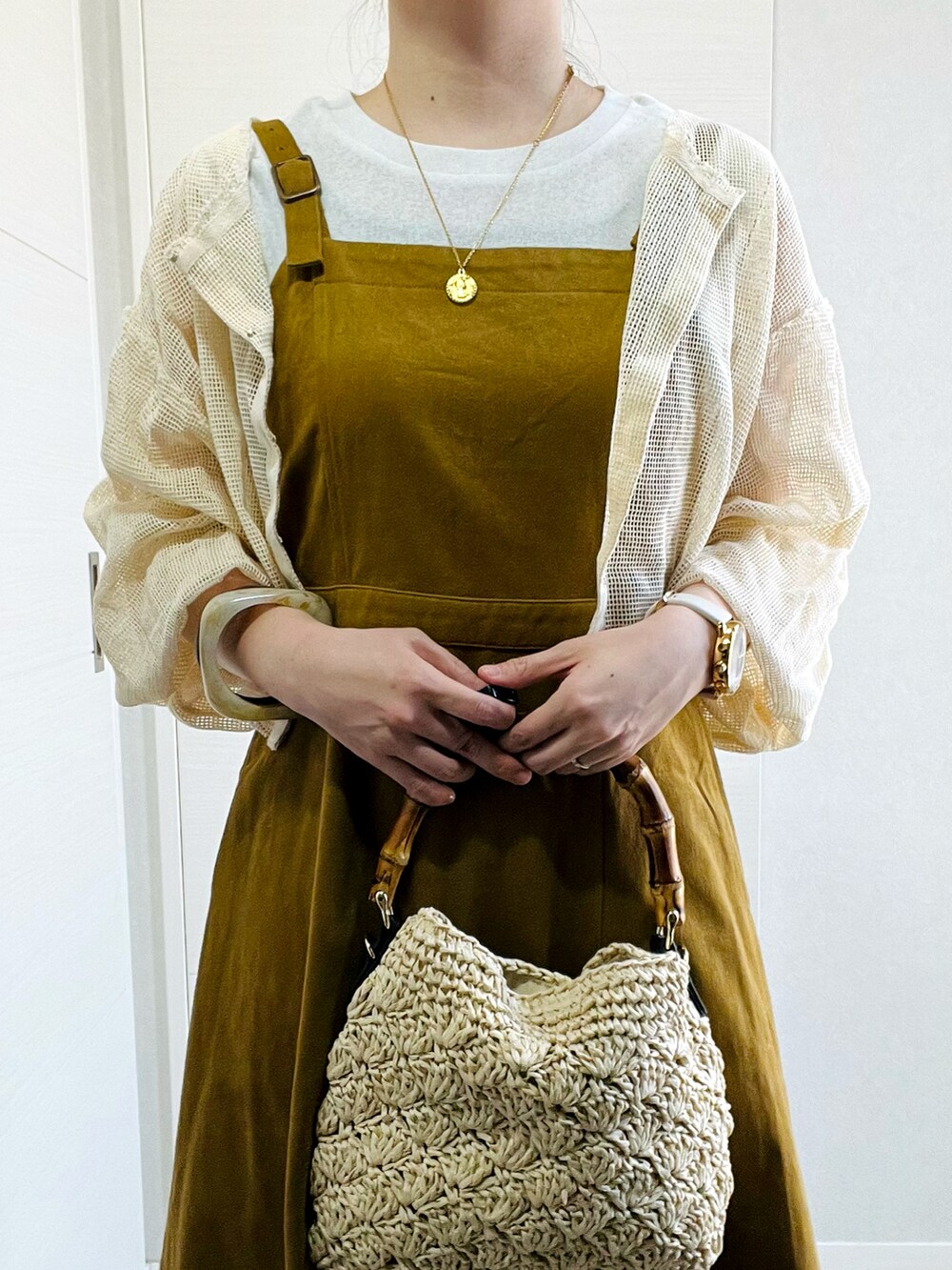 ホワイト系のカーディガン/ボレロ、イエロー系のワンピース、ブラック系のサンダルを着用したレディースの夏コーディネートの3枚目の写真