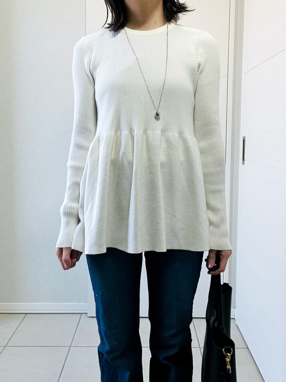 ホワイト系のニット/セーター、ブルー系のデニムパンツ、レッド系のスニーカーを着用したレディースの春コーディネートの2枚目の写真