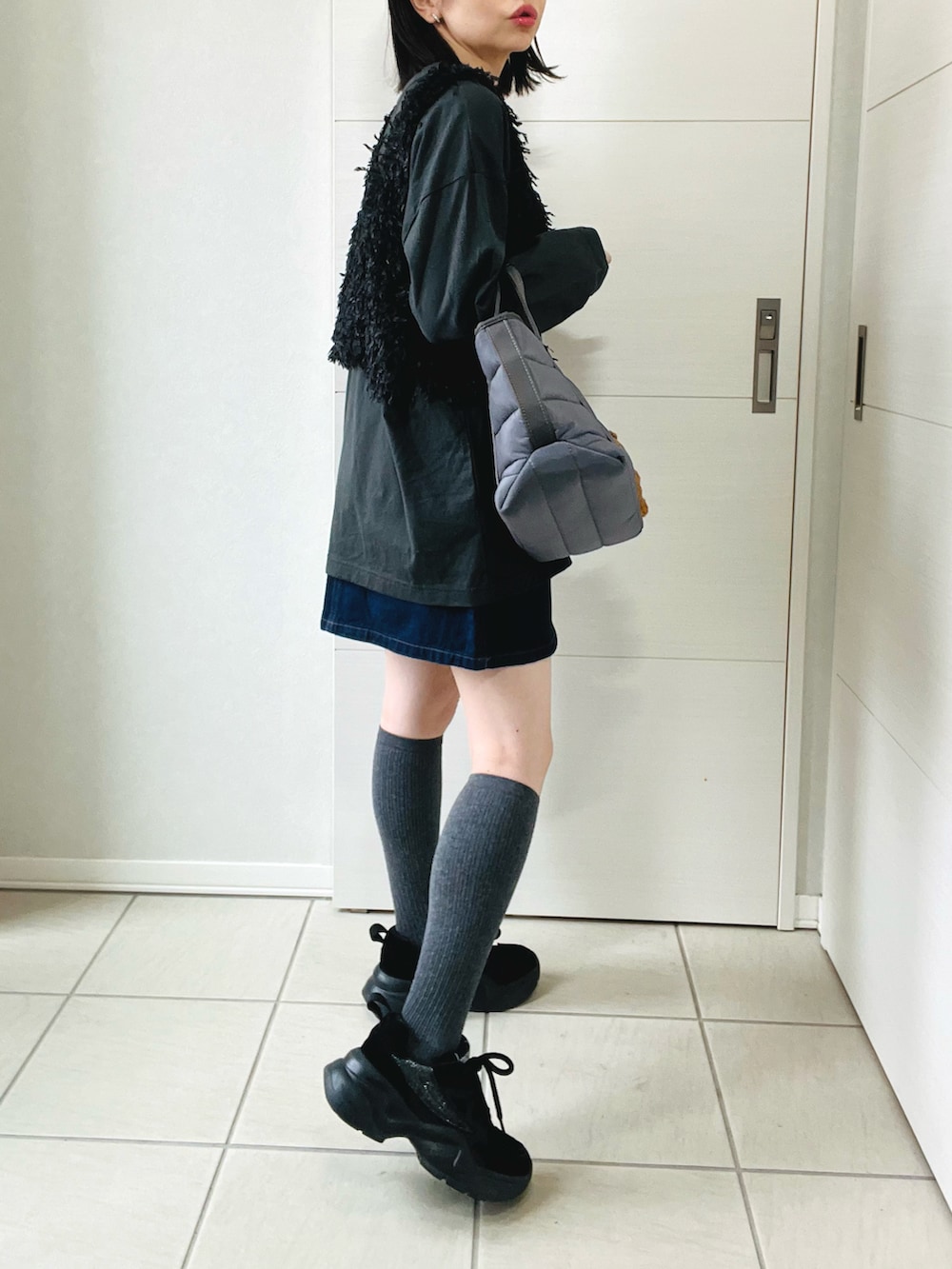 ブラック系のベスト、グレー系のTシャツ/カットソー、ブルー系のデニムスカートを着用したレディースの春コーディネートの4枚目の写真