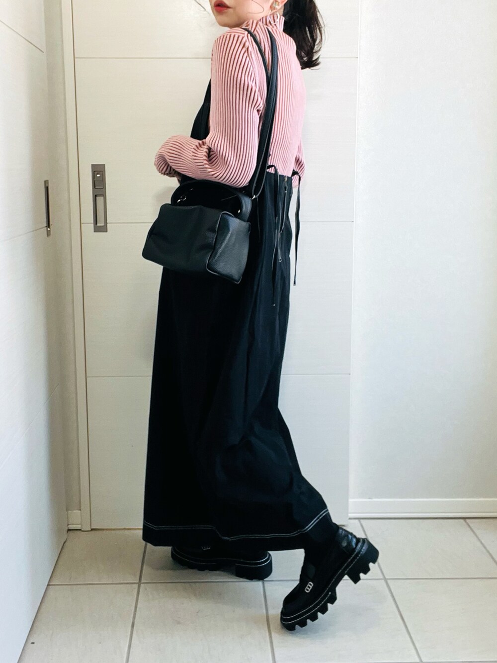 ピンク系のニット/セーター、ブラック系のワンピース、ブラック系のローファーを着用したレディースの春コーディネートの5枚目の写真
