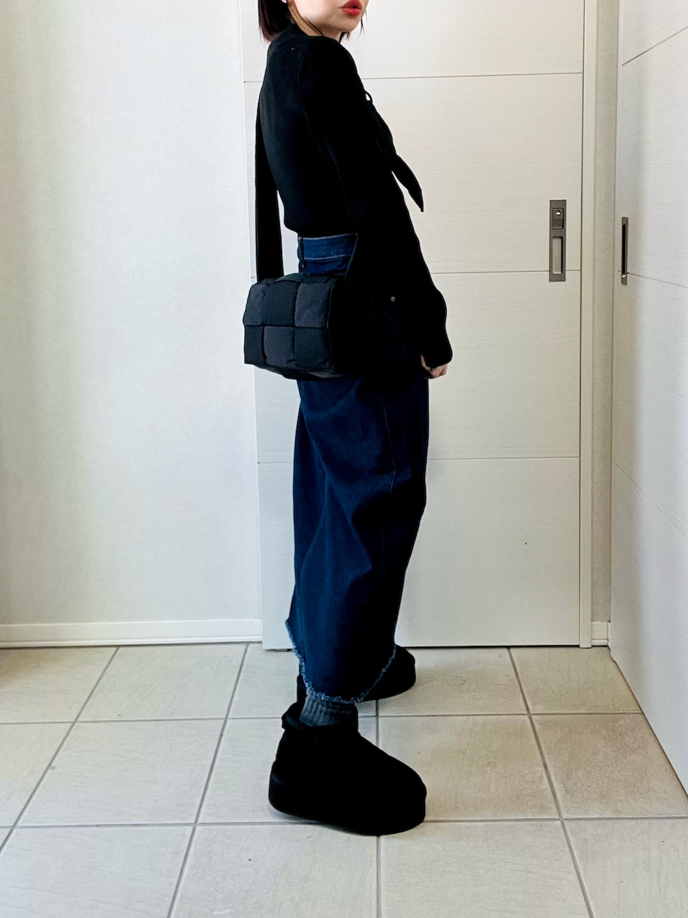 ブラック系のニット/セーター、ブルー系のスカート、ブラック系のブーツを着用したレディースの冬コーディネートの5枚目の写真