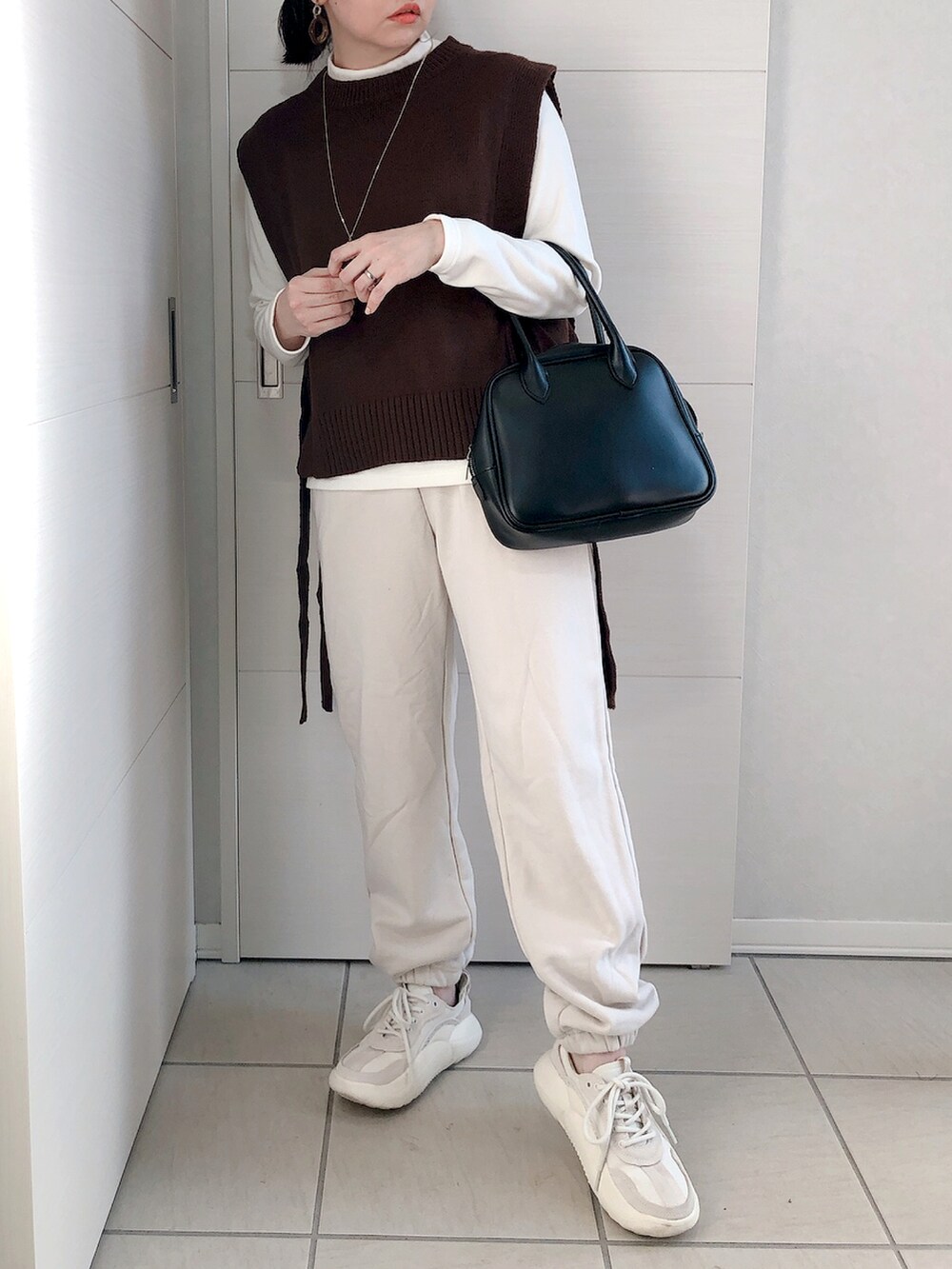 ブラウン系のベスト、ホワイト系のTシャツ/カットソー、ホワイト系のスウェットパンツを着用したレディースの冬コーディネートの2枚目の写真