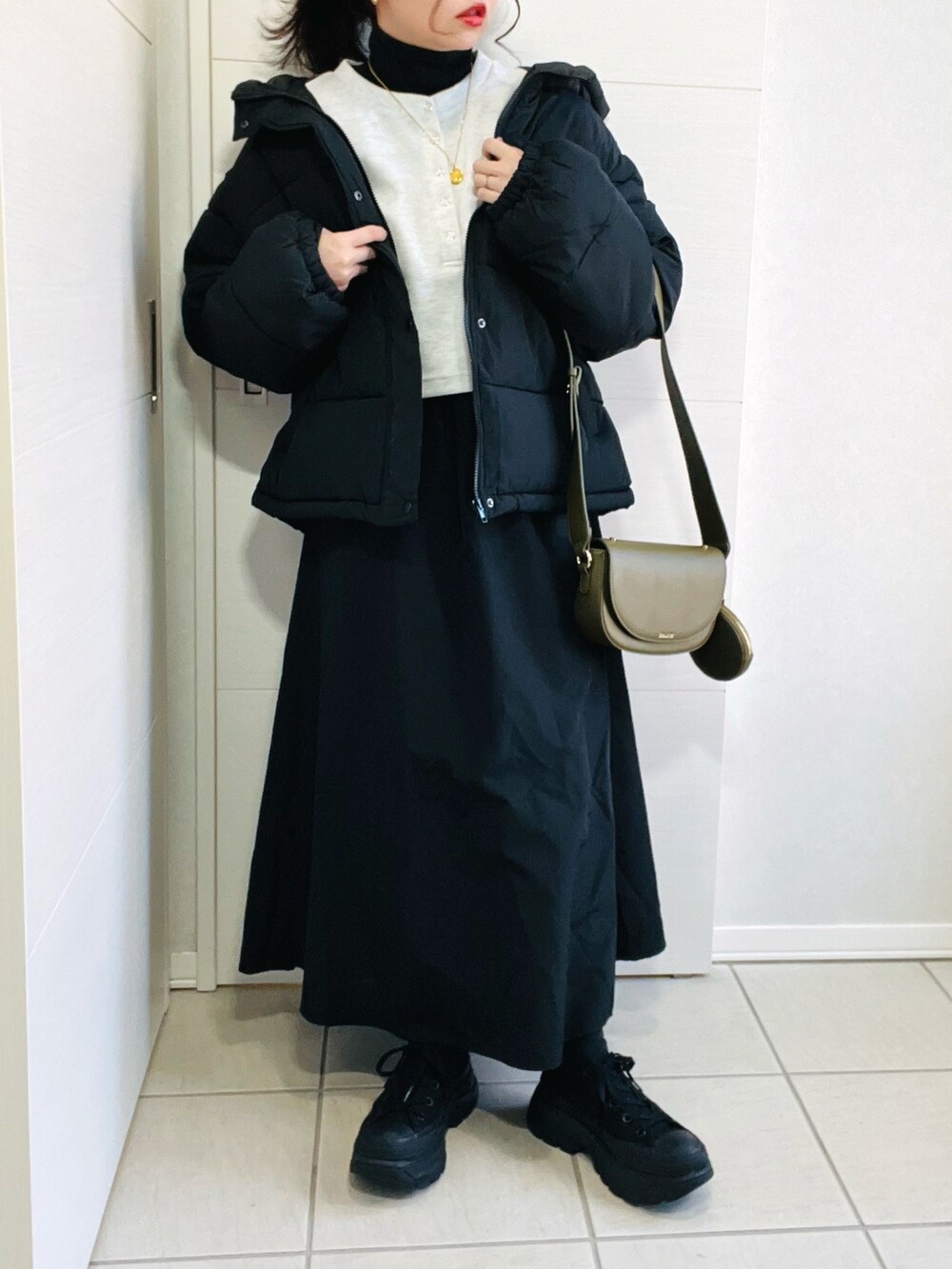 グレー系のワンピース、グリーン系のショルダーバッグ、ブラック系のスニーカーを着用したレディースの冬コーディネートの4枚目の写真
