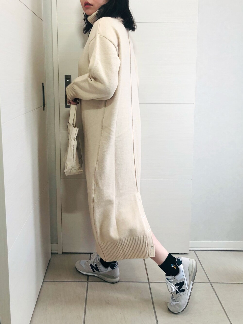 ブラウン系のノーカラーコート、ホワイト系のワンピース、ホワイト系のスニーカーを着用したレディースの秋コーディネートの3枚目の写真