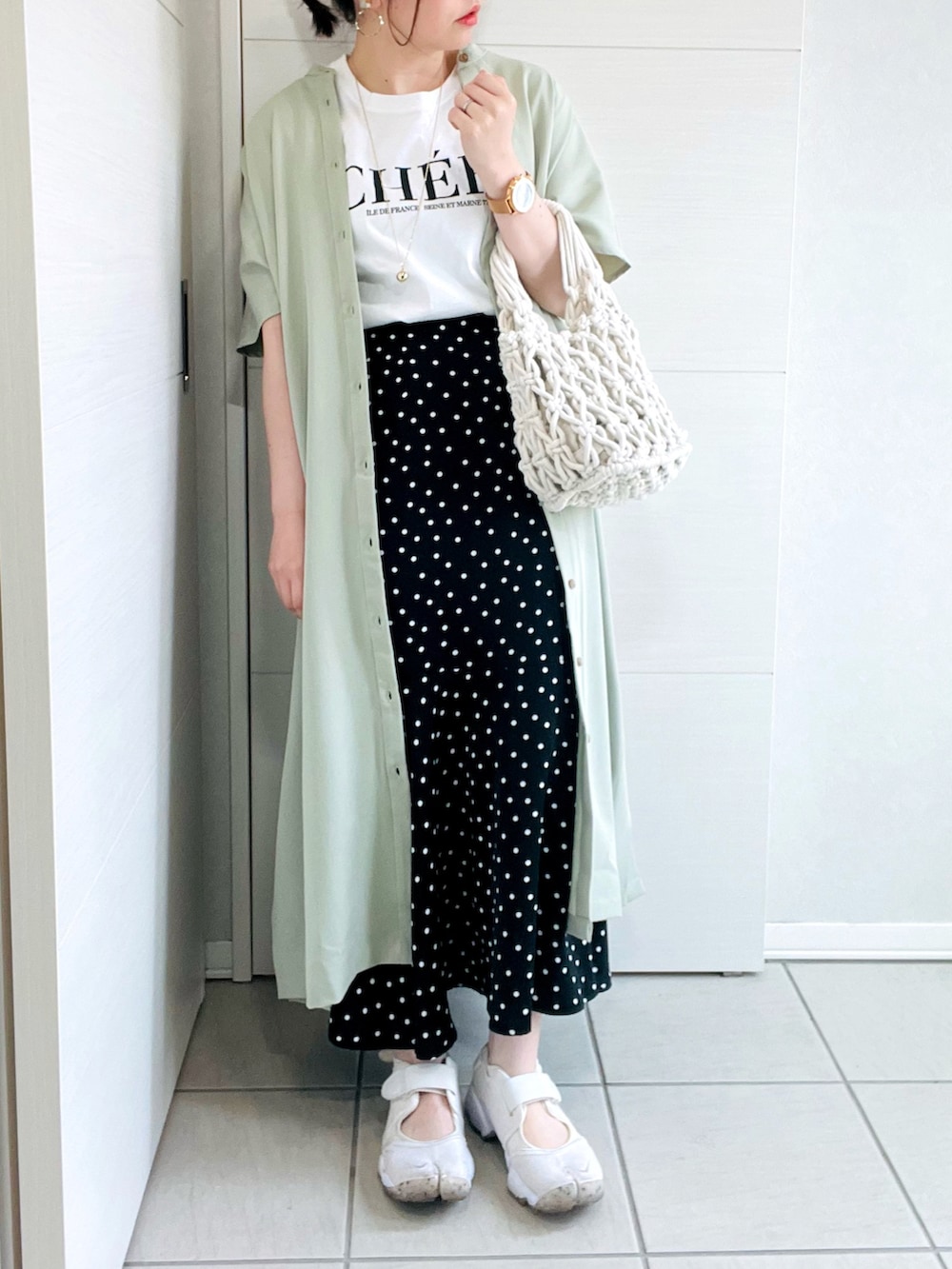 ホワイト系のTシャツ/カットソー、グリーン系のワンピース、ブラック系のスカートを着用したレディースの春コーディネートの2枚目の写真