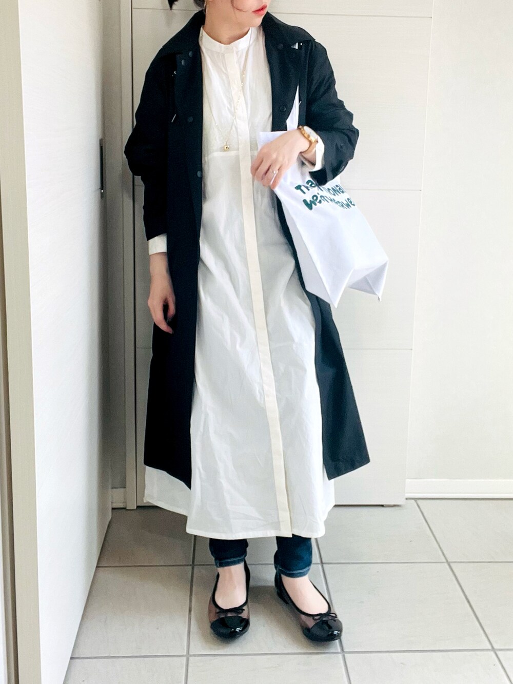 ホワイト系のシャツワンピース、ブラック系のバレエシューズ、ホワイト系のトートバッグを着用したレディースの春コーディネートの2枚目の写真