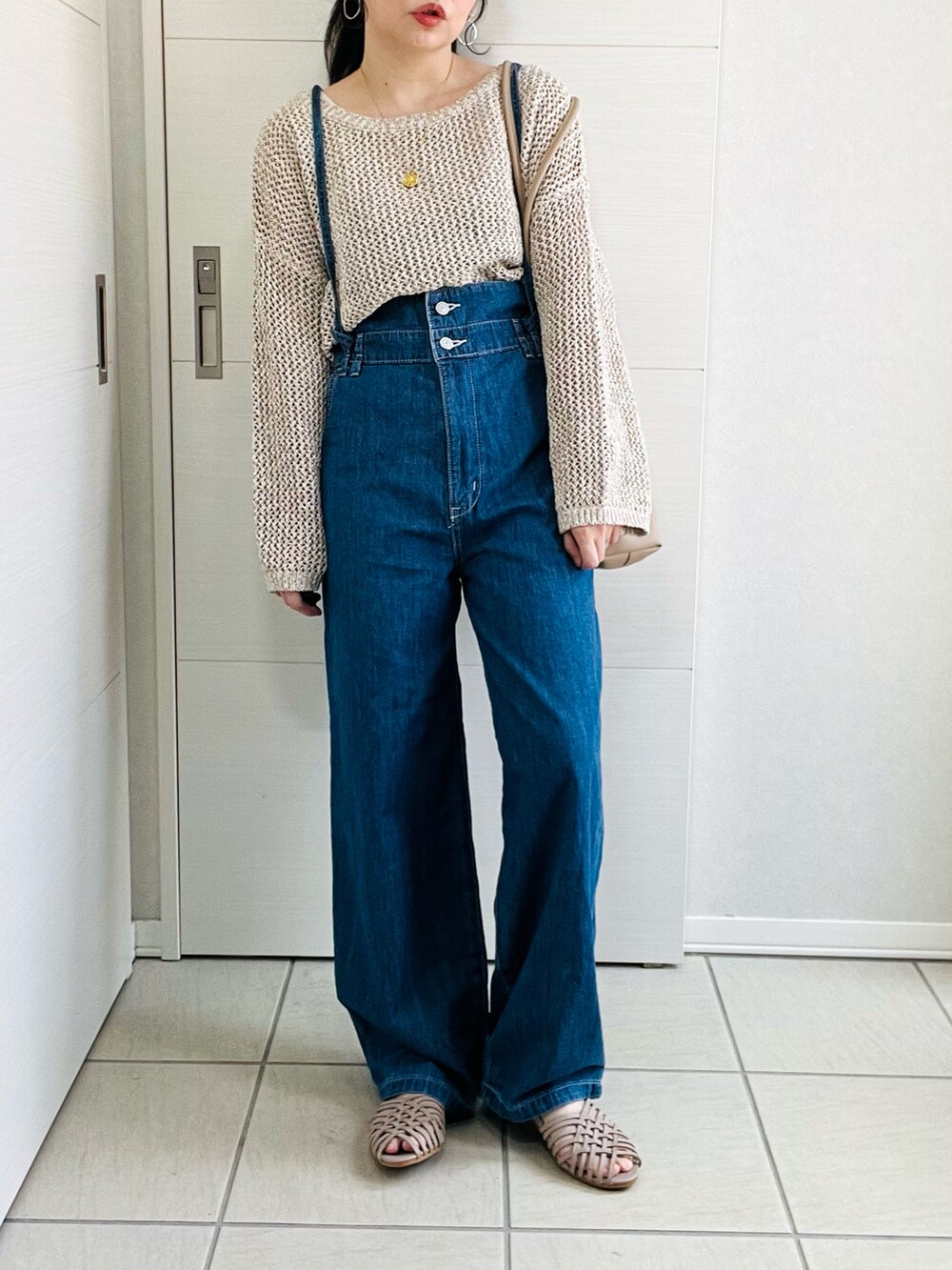 ブルー系のサロペット/オーバーオール、ベージュ系のニット/セーター、グレー系のサンダルを着用したレディースの春コーディネートの2枚目の写真