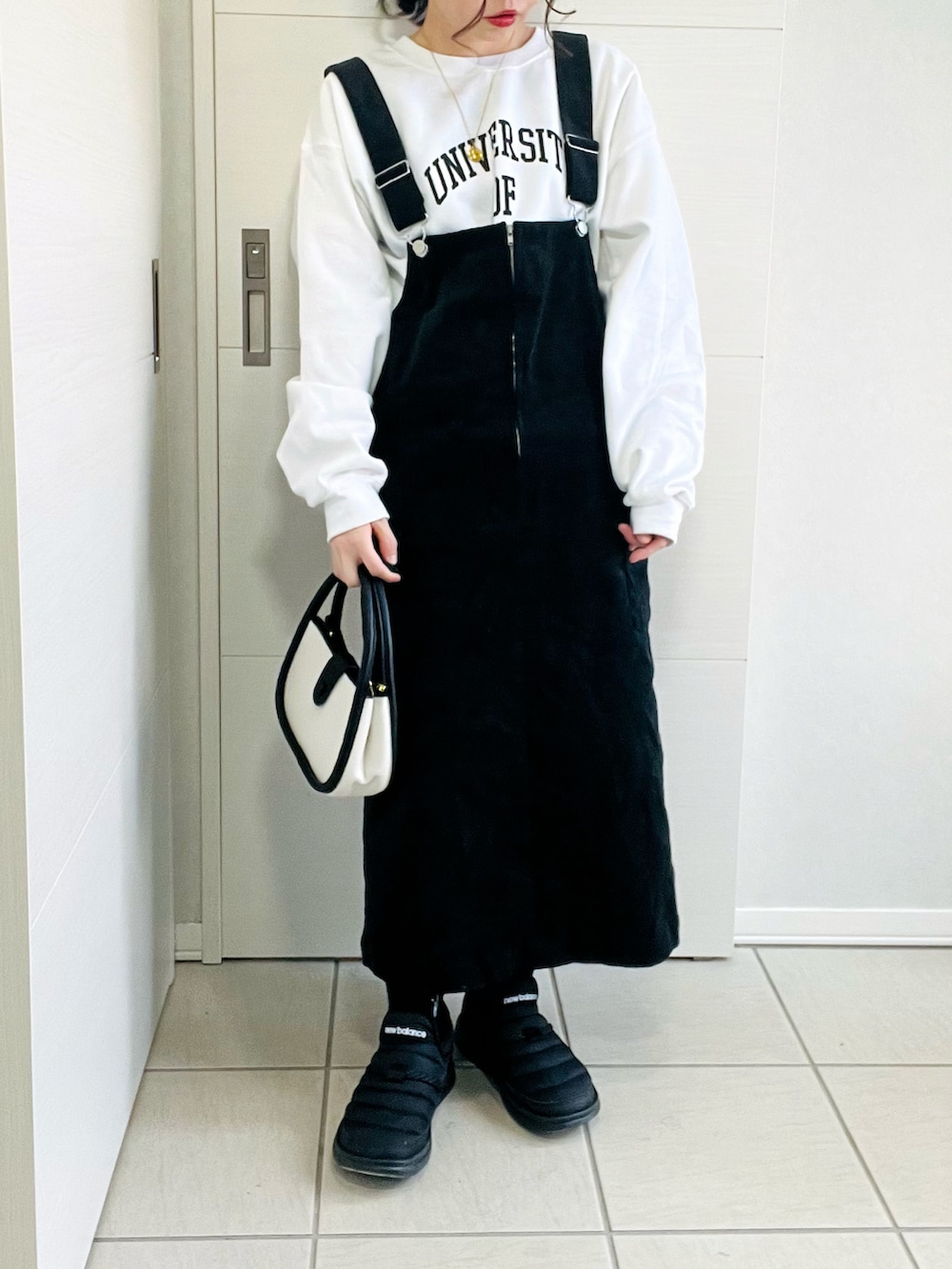 ホワイト系のダウンジャケット/コート、ホワイト系のスウェット、ブラック系のジャンパースカートを着用したレディースの冬コーディネートの2枚目の写真