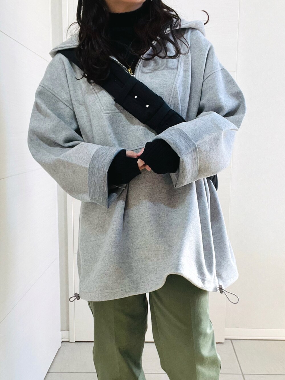 グレー系のパーカー、ブラック系のニット/セーター、グリーン系のチノパンツを着用したレディースの冬コーディネートの3枚目の写真