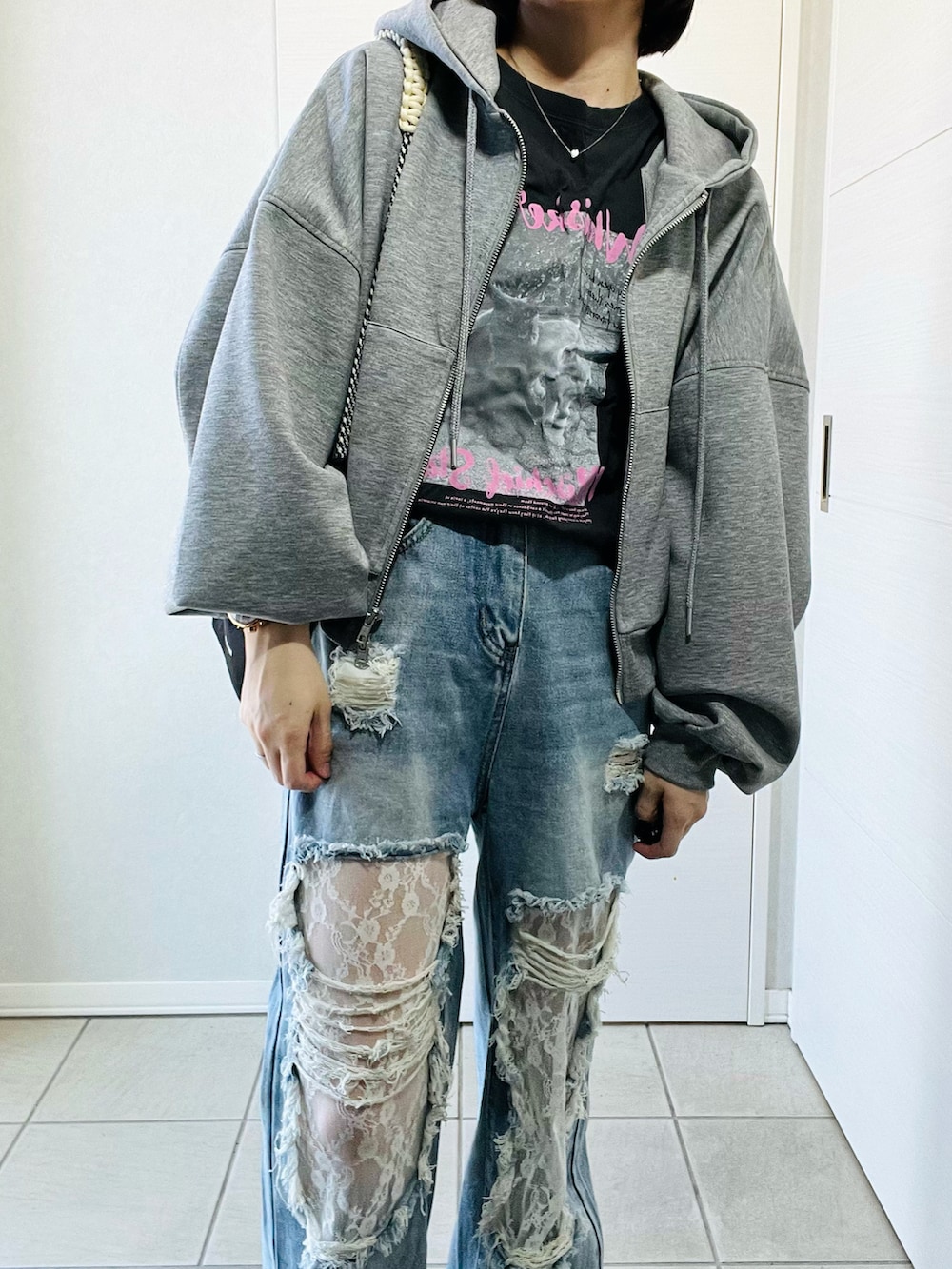 グレー系のパーカー、グレー系のTシャツ/カットソー、ブルー系のデニムパンツを着用したレディースの冬コーディネートの2枚目の写真