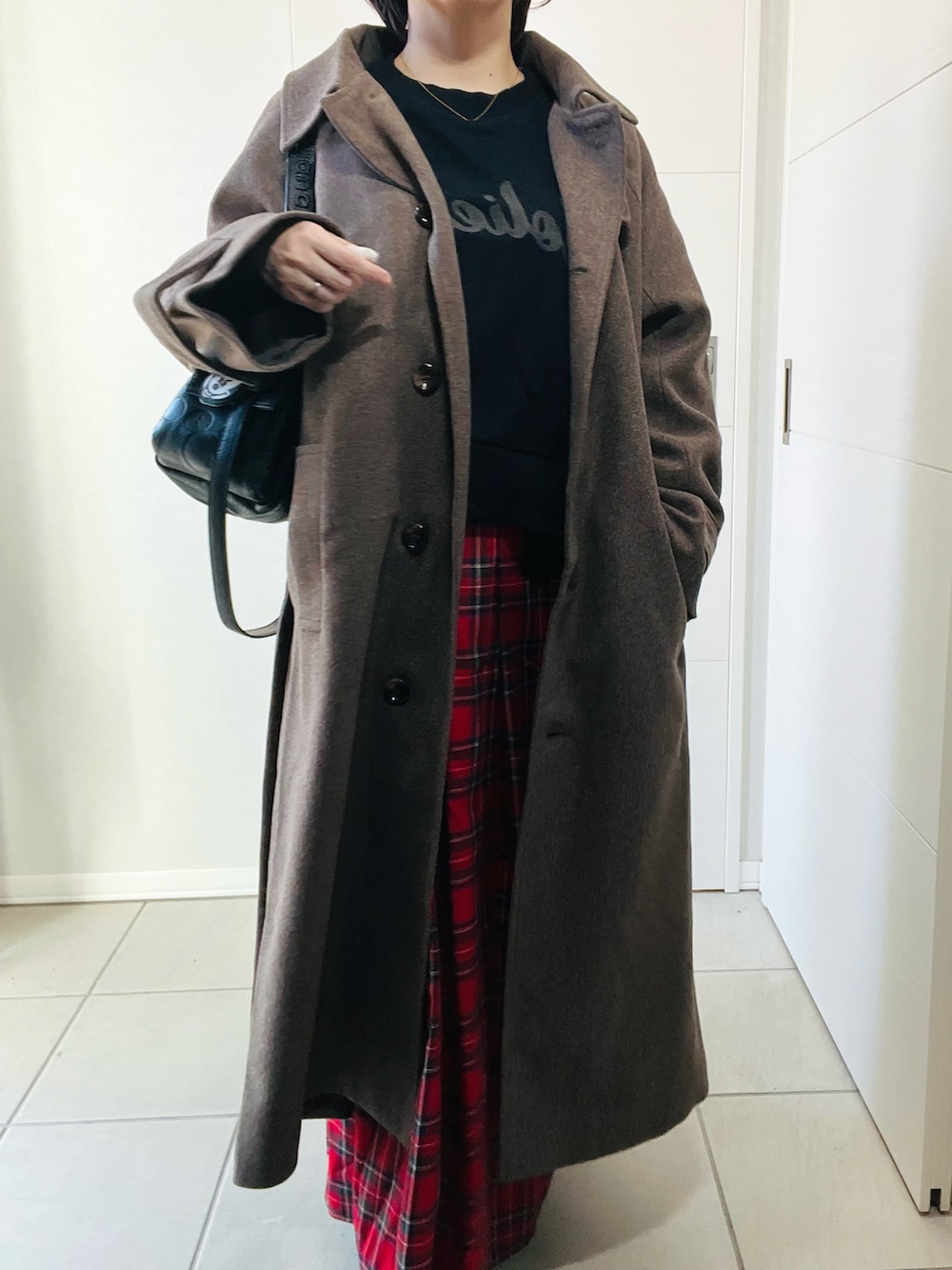ブラウン系のステンカラーコート、ブラック系のスウェット、レッド系のスカートを着用したレディースの秋コーディネートの2枚目の写真