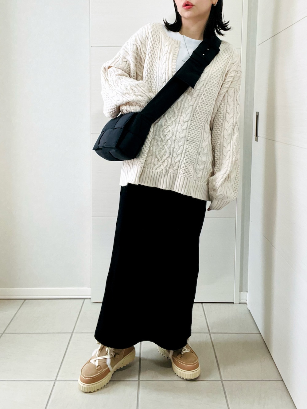 ホワイト系のニット/セーター、ブラック系のスカート、ブラウン系のブーツを着用したレディースの冬コーディネートの2枚目の写真