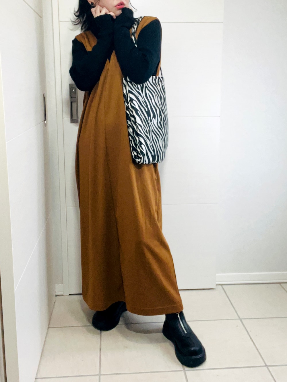 ブラウン系のサロペット/オーバーオール、ブラック系のニット/セーター、ブラック系のブーツを着用したレディースの秋コーディネートの3枚目の写真