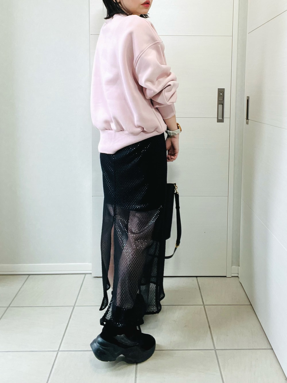 ピンク系のスウェット、ブラック系のスカート、ブラック系のスニーカーを着用したレディースの冬コーディネートの2枚目の写真